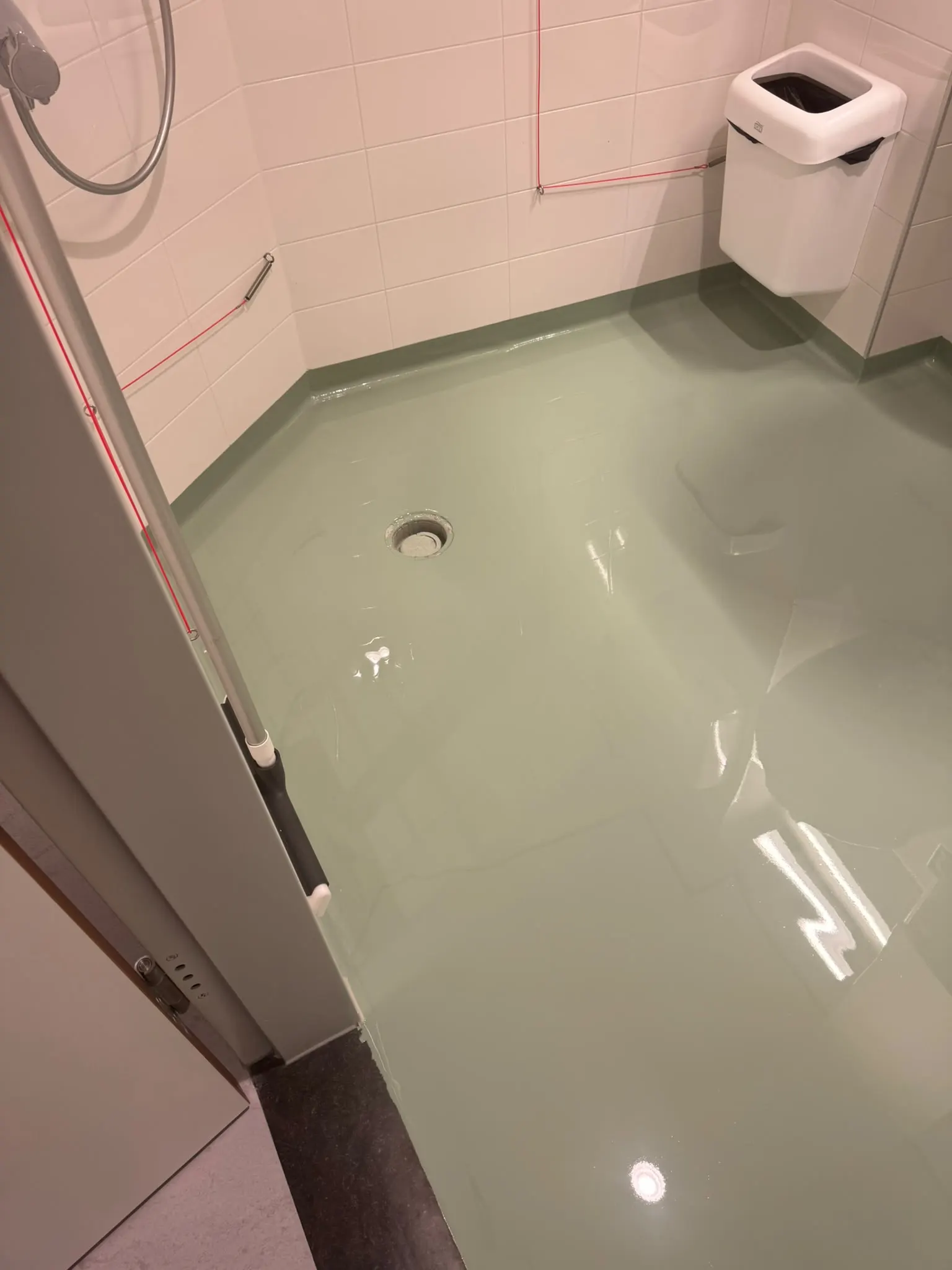 Sanitaire ruimte met een glanzende gietvloer in een saliegroene tint