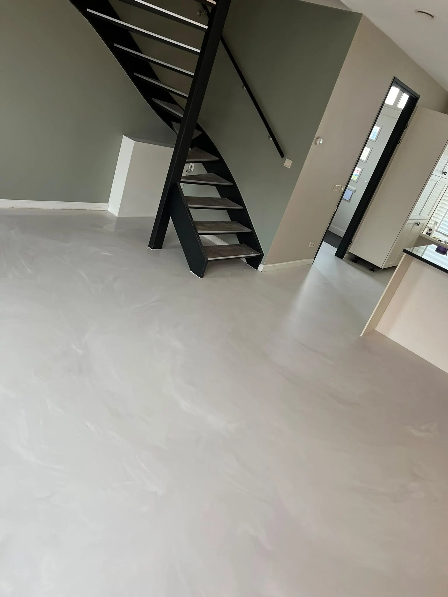 Woning met een lichtgrijze, naadloze gietvloer en een trap