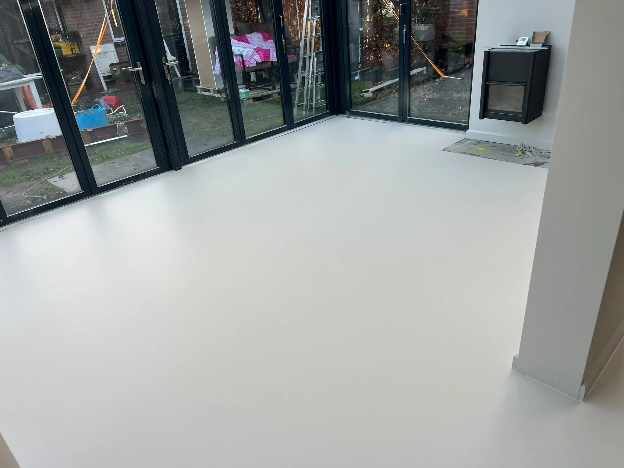 Woonkamer met een naadloze, lichte gietvloer en openslaande glazen deuren